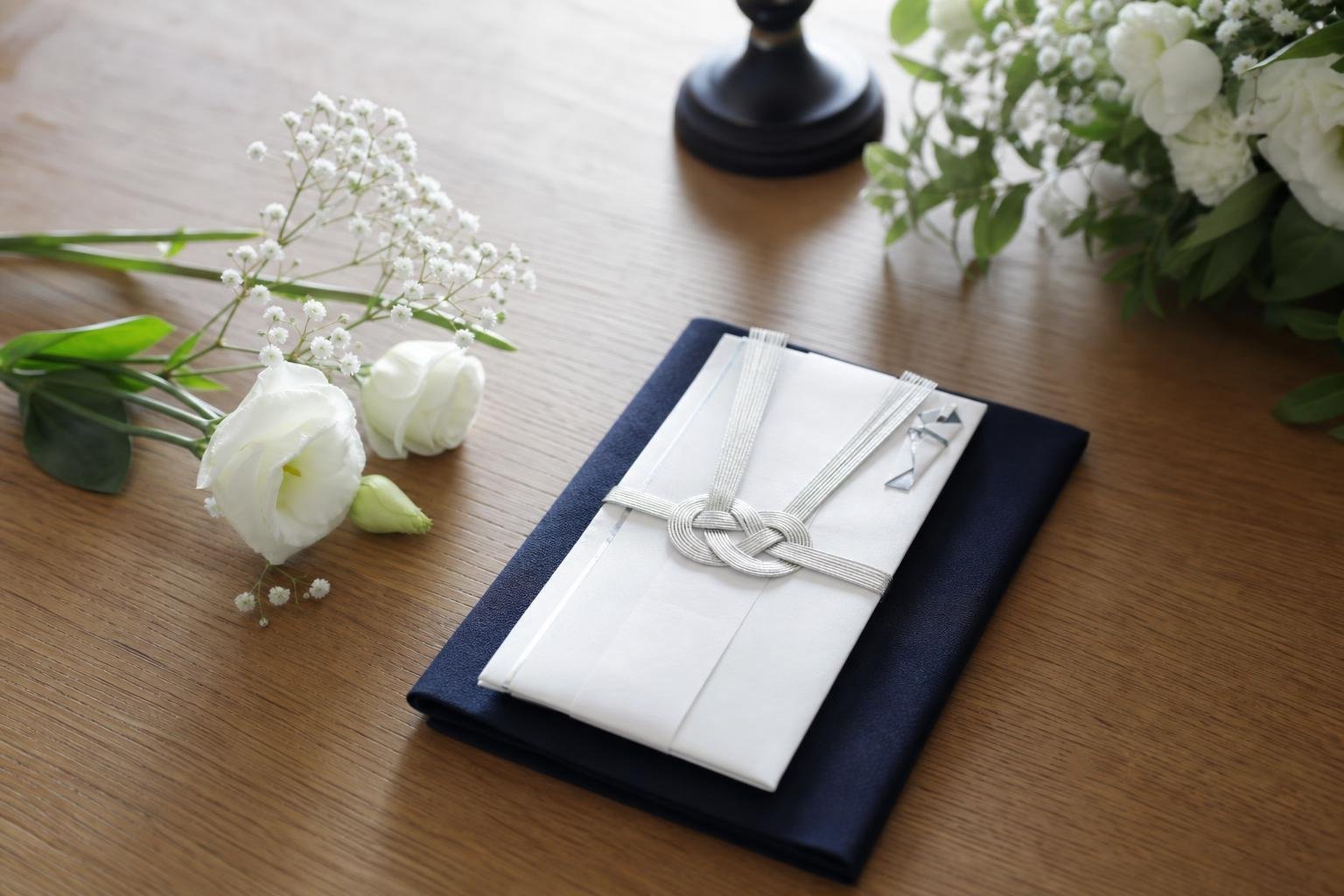A white condolence envelope and a fukusa (wrapping cloth) are neatly placed on a wooden table.